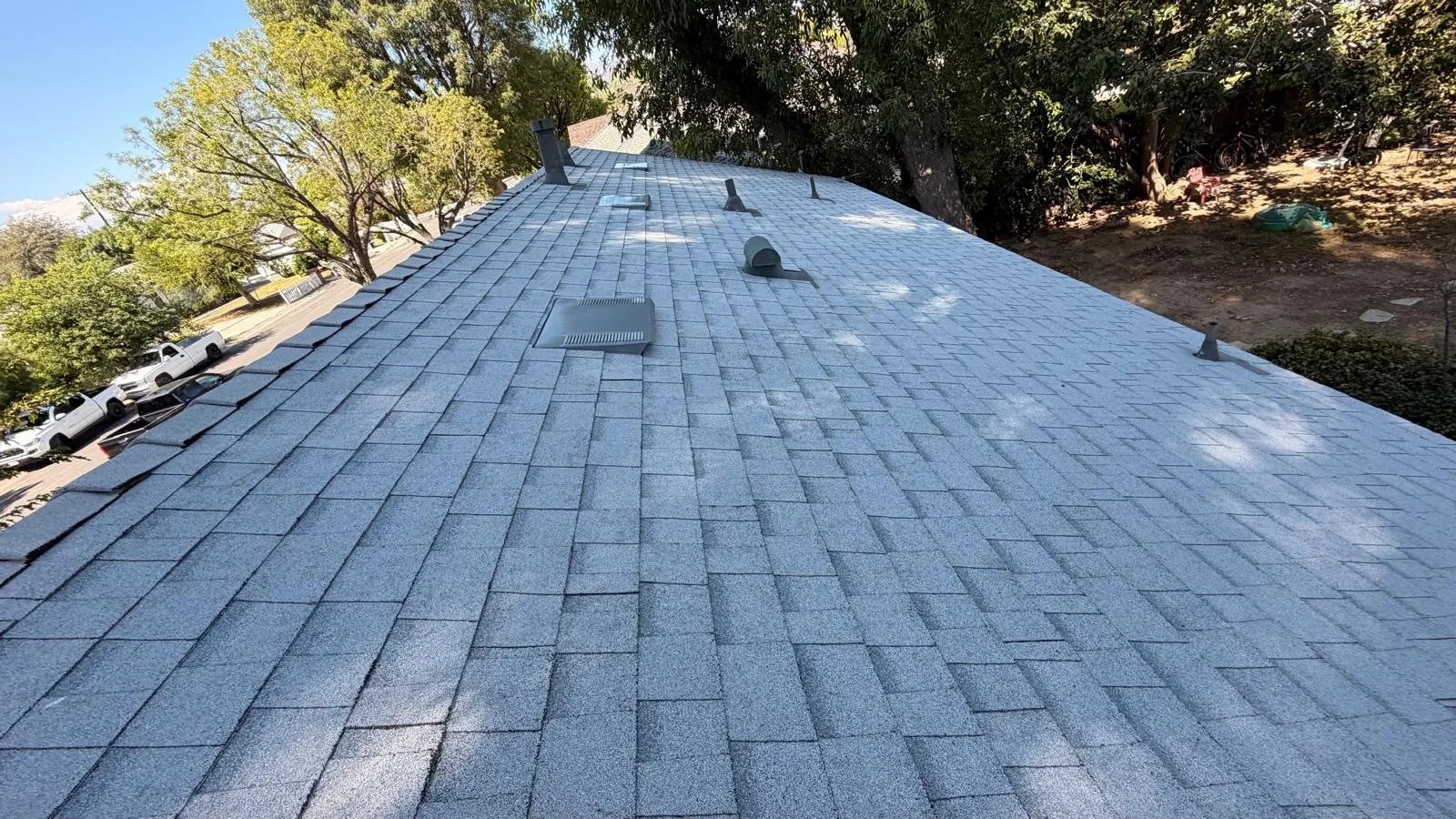 Long slope of new Shasta White cool roof shingles with roof vents and pipe flashings in Northridge