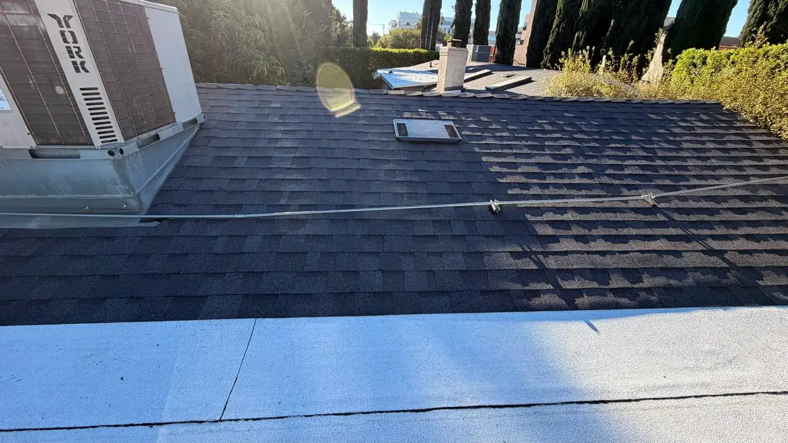 Dark cool roof shingles running past rooftop air conditioning equipment in Encino