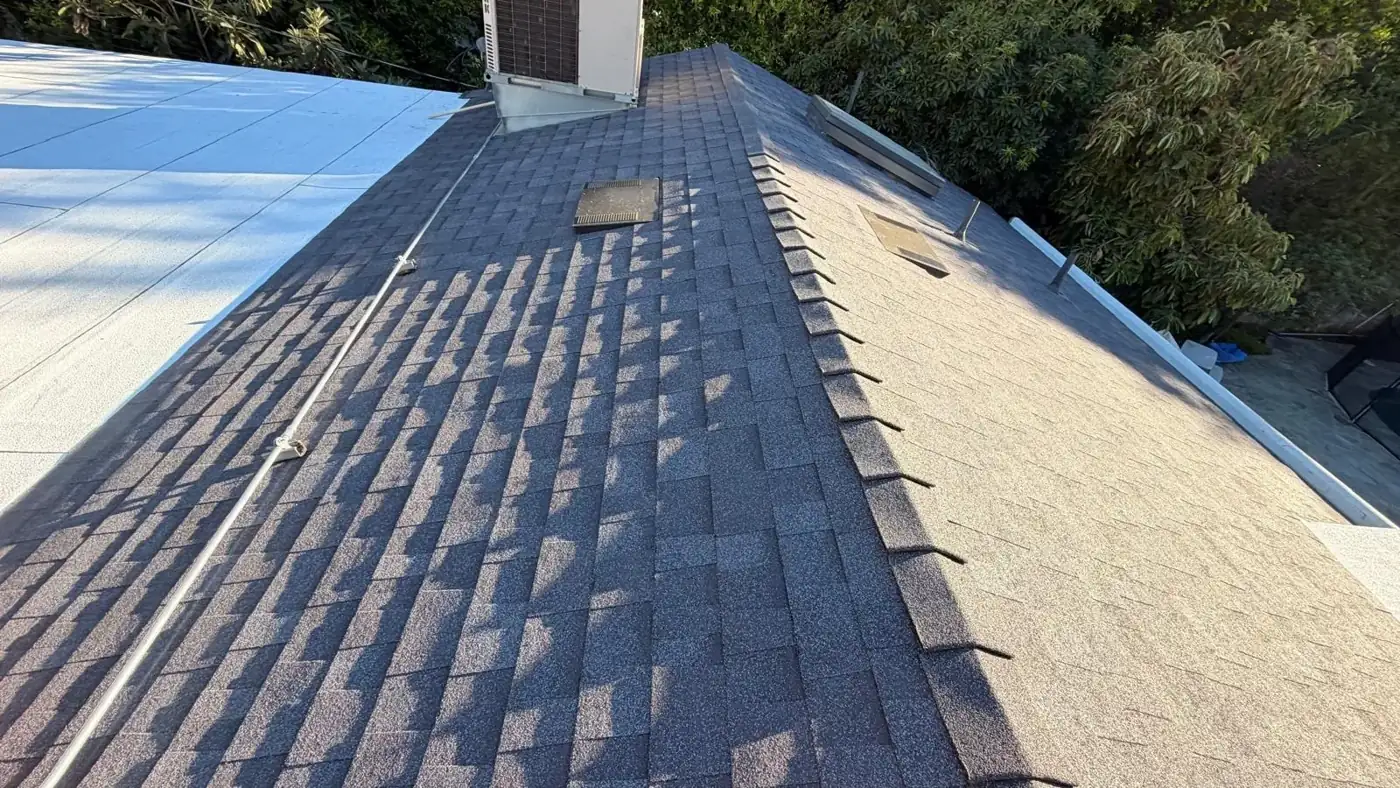 Hip ridge of new Midnight shingles next to a white flat roof in Encino