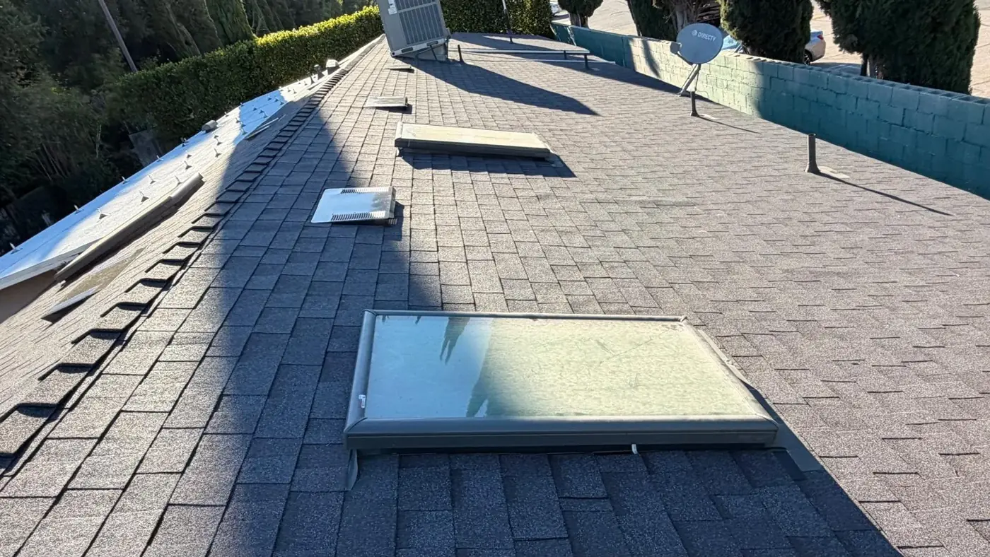 Long slope of Midnight cool roof shingles with skylights and vents on an Encino roof