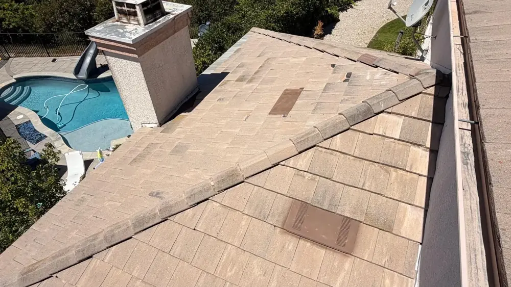 Finished concrete tile slope with hip ridge, vents and chimney above the back yard