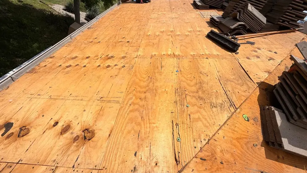 Original plywood roof deck with dark water stains after the tile and old underlayment were removed