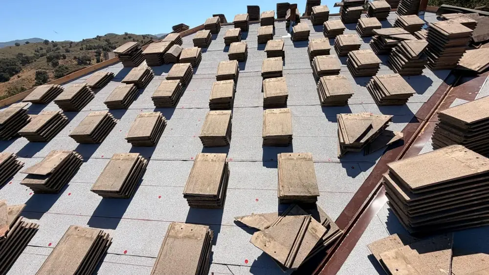 Full slope of new cap sheet underlayment in Agoura Hills with concrete tile stacks spread across it
